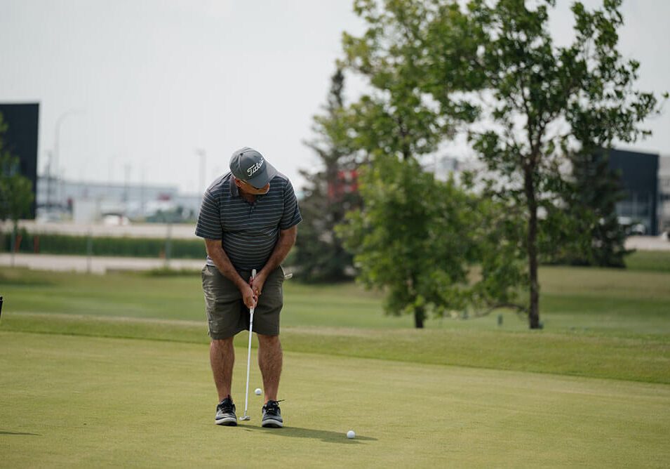 Man putting golf ball on green