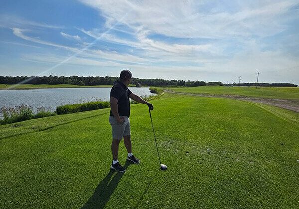 Man golfing by a lake
