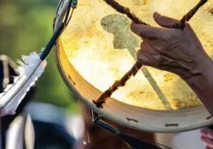 Hand playing a traditional drum outdoors