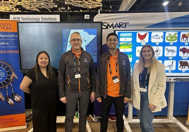 Four people posing at technology conference booth